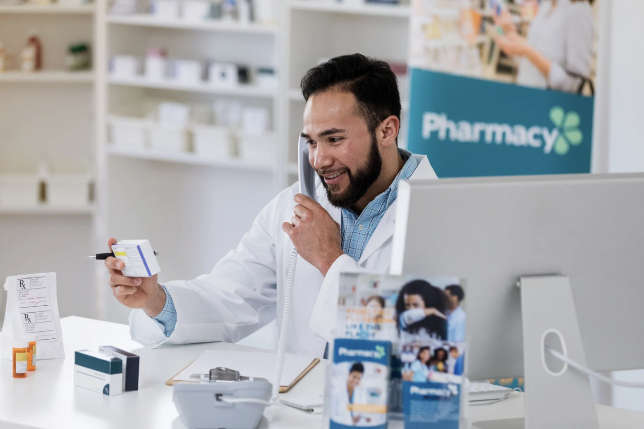 A pharmacist at Ivywild Pharmacy reviewing a medication while assisting a patient by phone