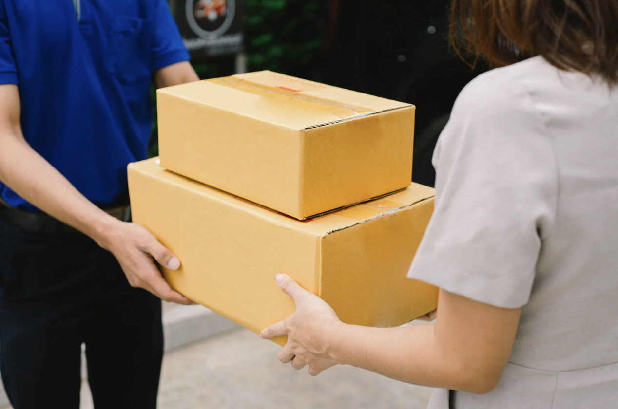 A delivery courier handing packaged prescriptions to a patient at their door